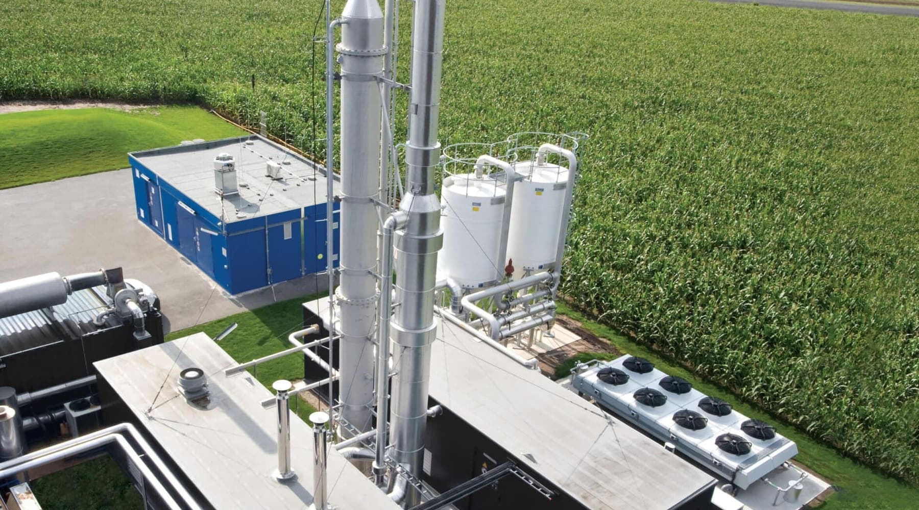 Aerial view of a compact carbon capture plant, its two columns and amine tanks standing beside a field