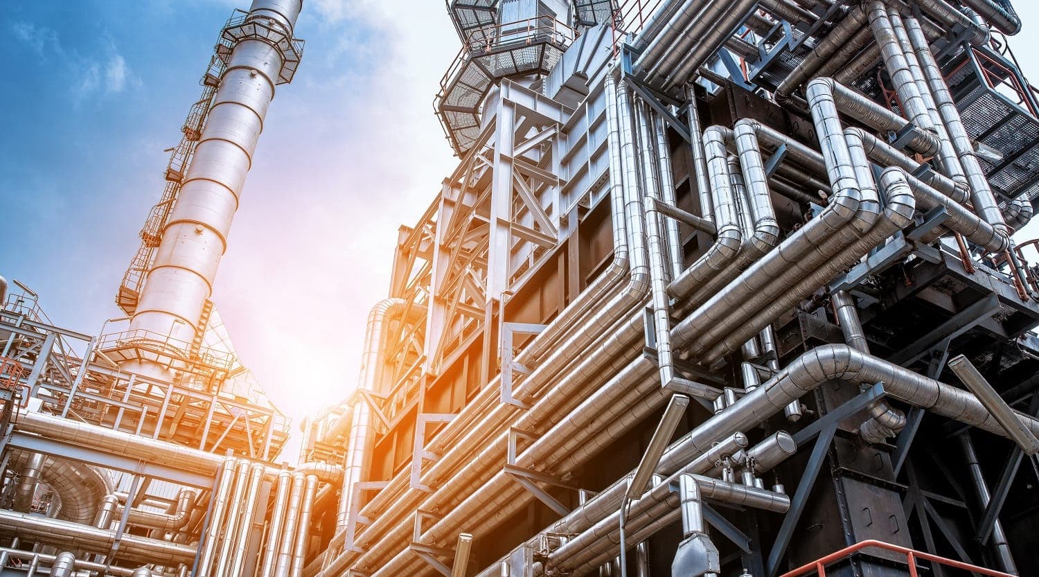 Process piping and columns seen from below against a bright sky